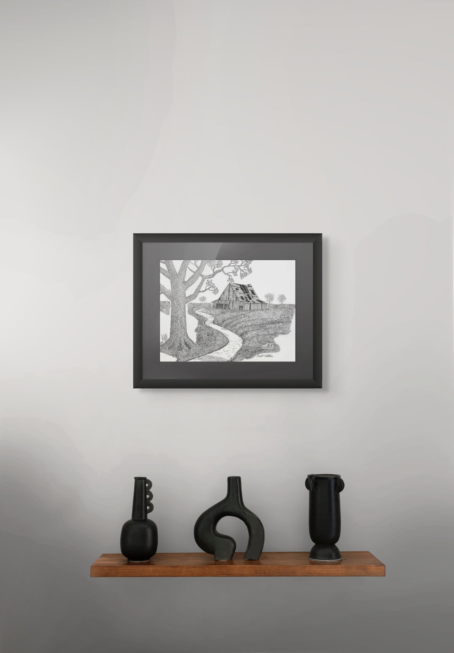 Framed black and white artwork on a gray wall with decorative vases below.