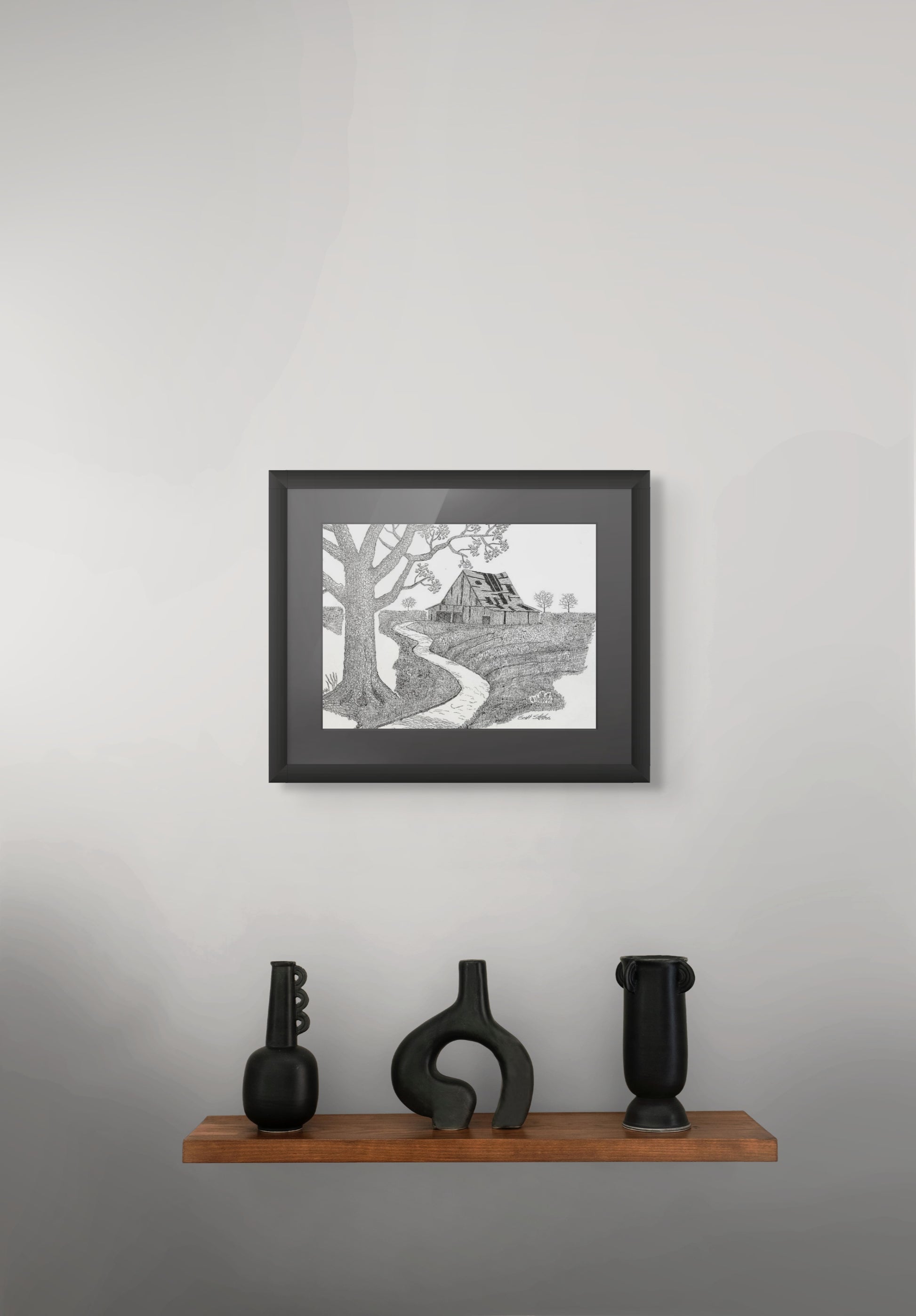 Framed black and white artwork on a gray wall with decorative vases below.