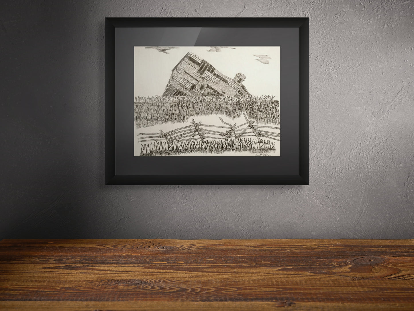 Framed black and white drawing of a landscape with a structure on a gray wall.