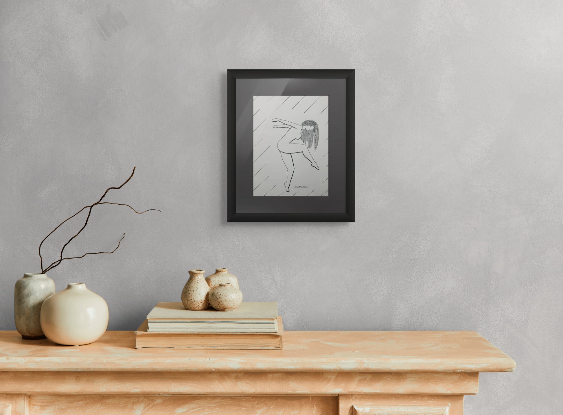 Framed artwork on a wall above a wooden console table with decorative items.