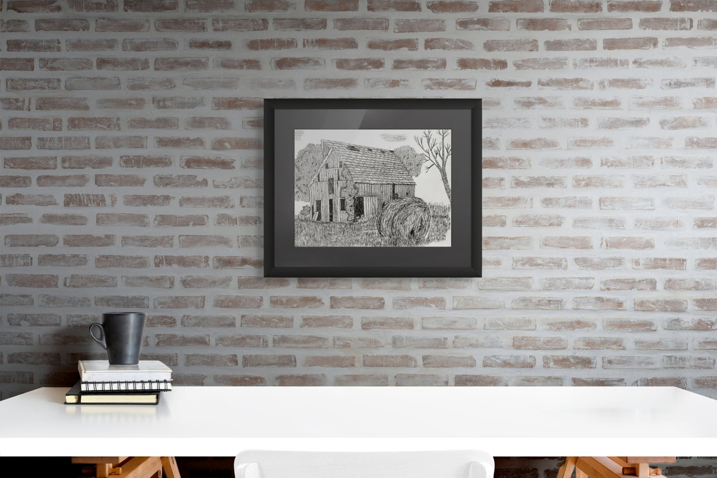 Famed pen and ink art print of an old barn with a large haybale in the foreground.