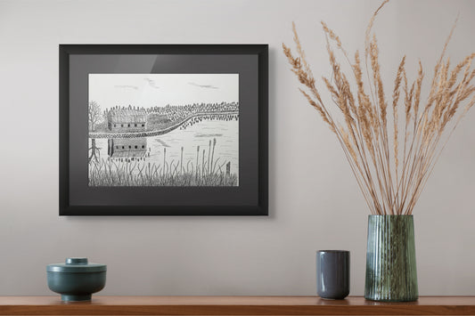 Framed black and white print on a wall above a wooden shelf with decorative items.