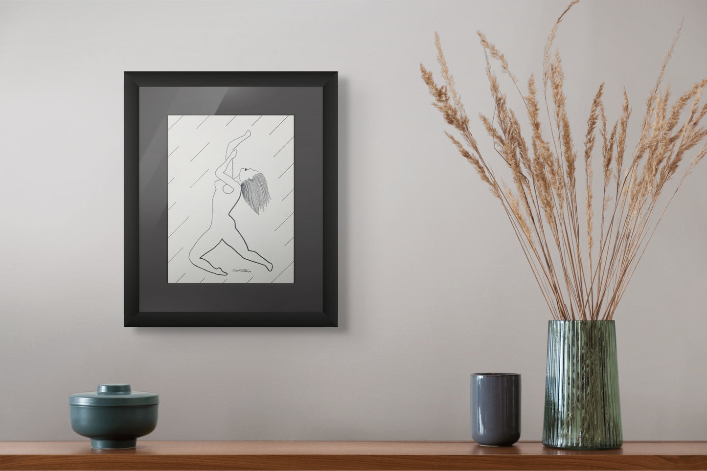 Framed artwork on a wall with decorative vases and plants below.