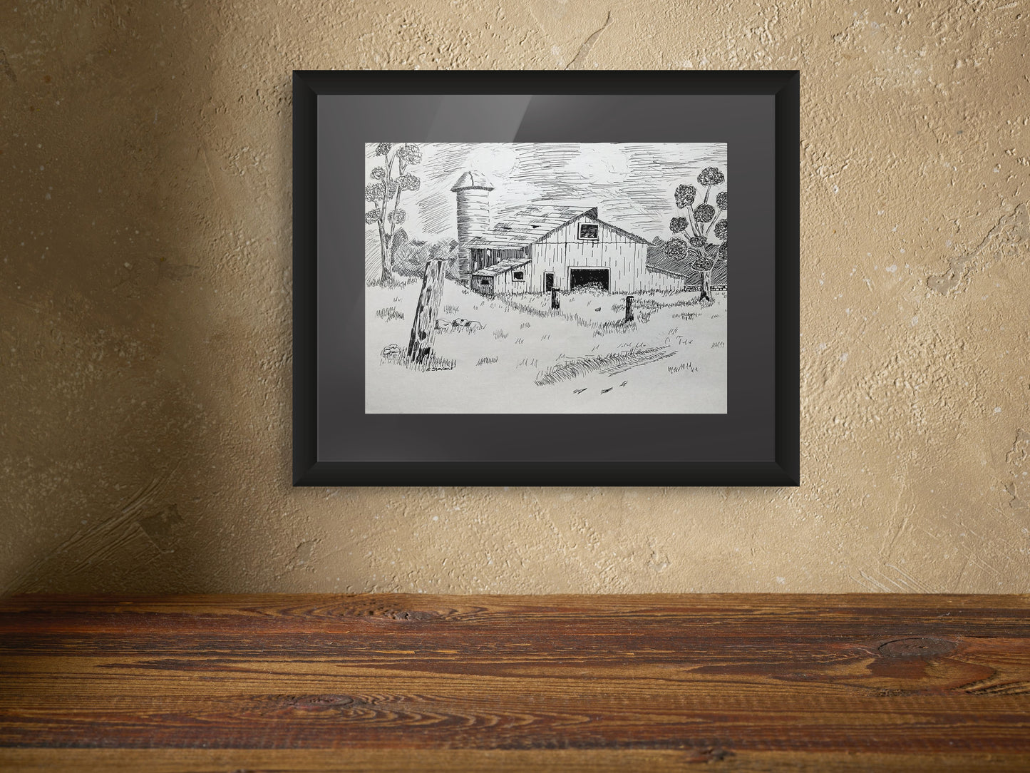 Framed black and white drawing of a farm scene on a textured wall.