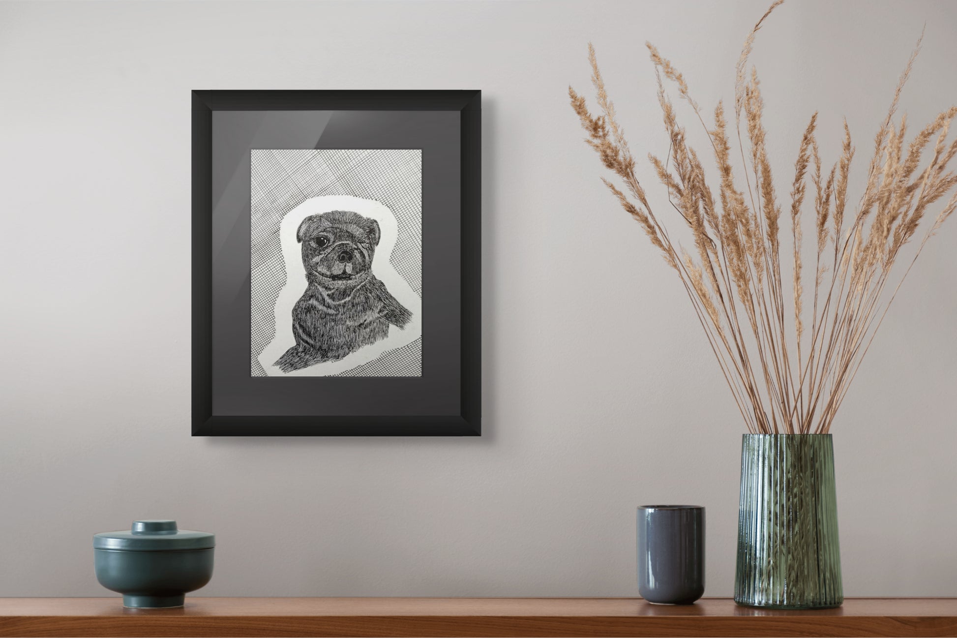 Framed black and white dog portrait on a wall above a wooden shelf with decorative items.
