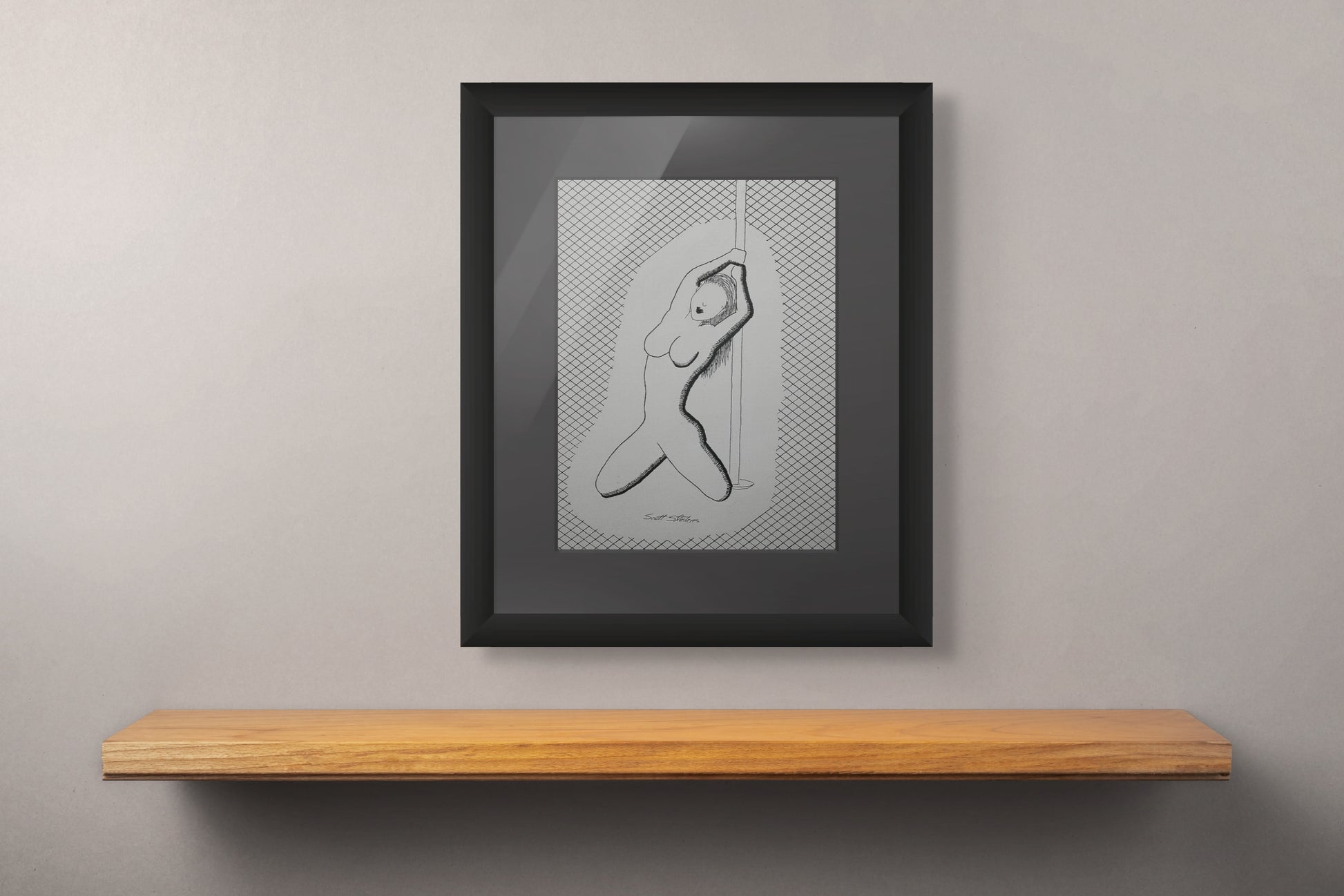 Framed artwork of a nude figure on a wooden shelf against a gray wall