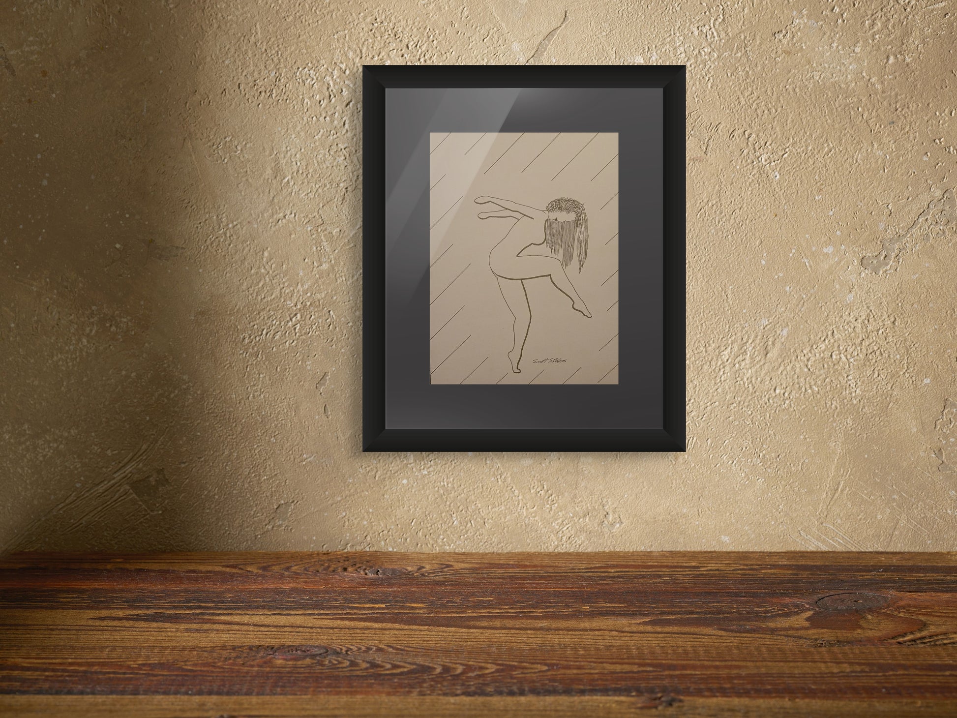 Framed artwork of a dancer on a textured wall above a wooden surface