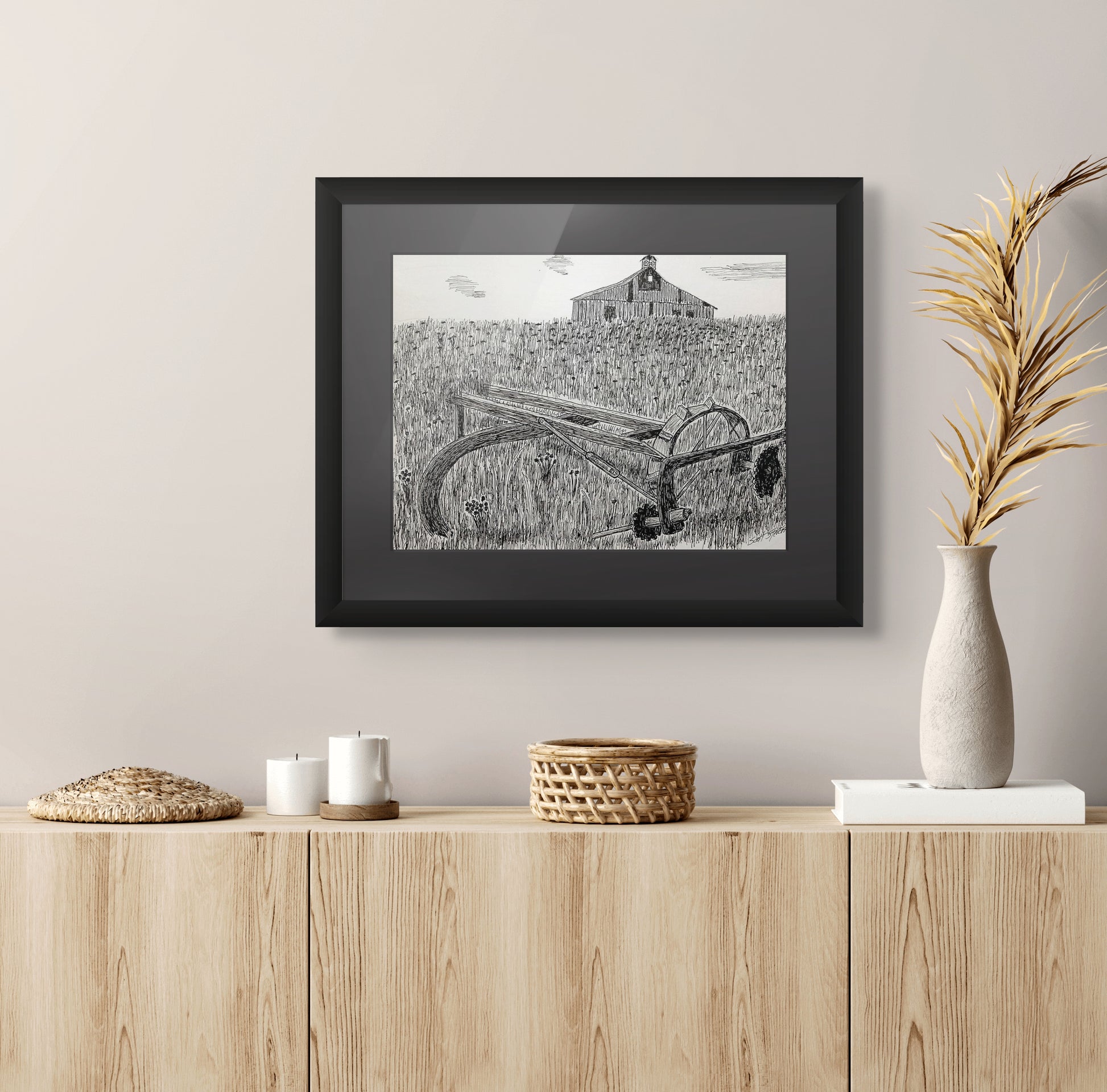 Framed pen and ink art print of an old plow in an overgrown field with a barn in the background.