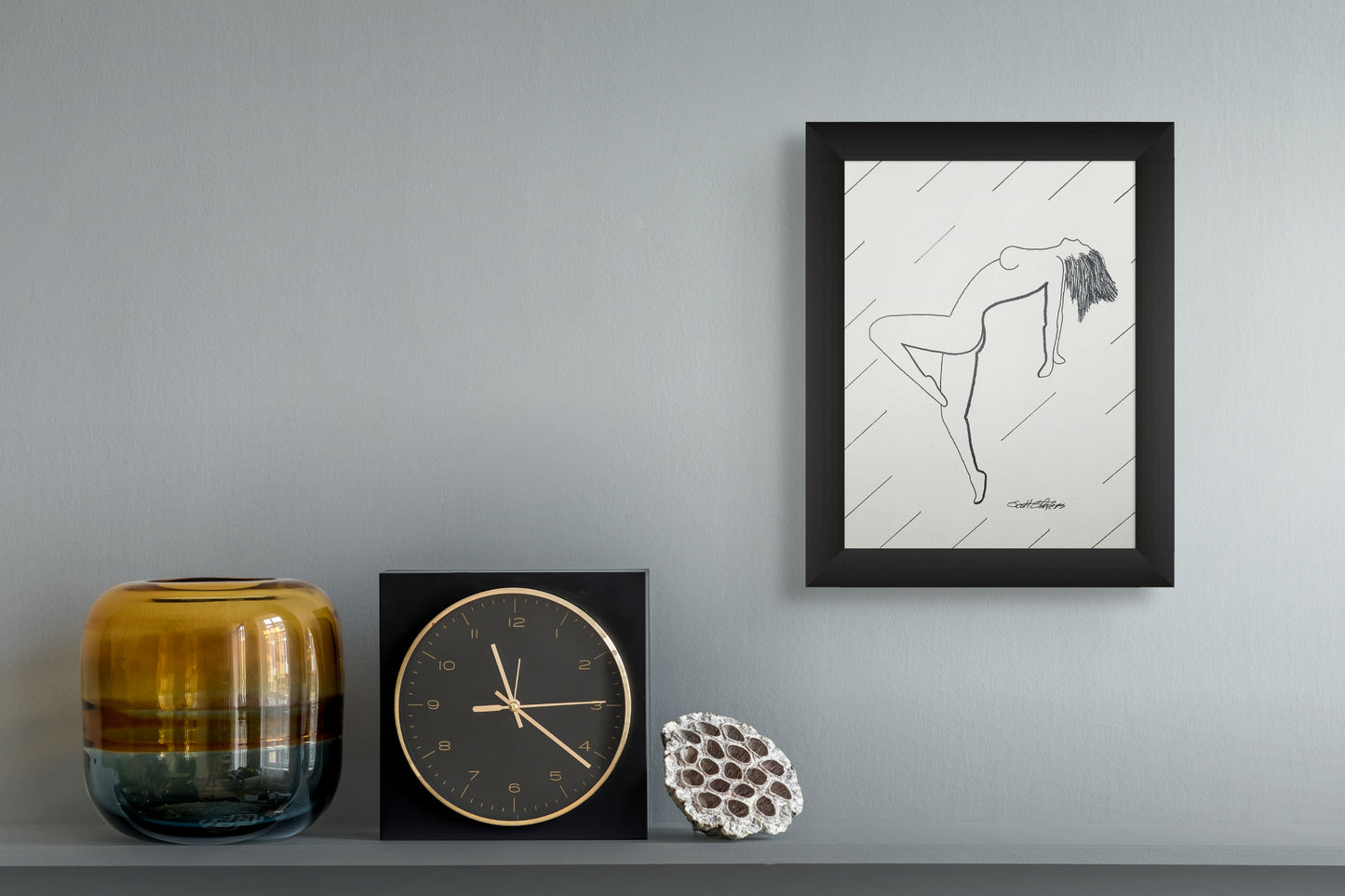Framed artwork of a dancer on a wall with decorative items below.