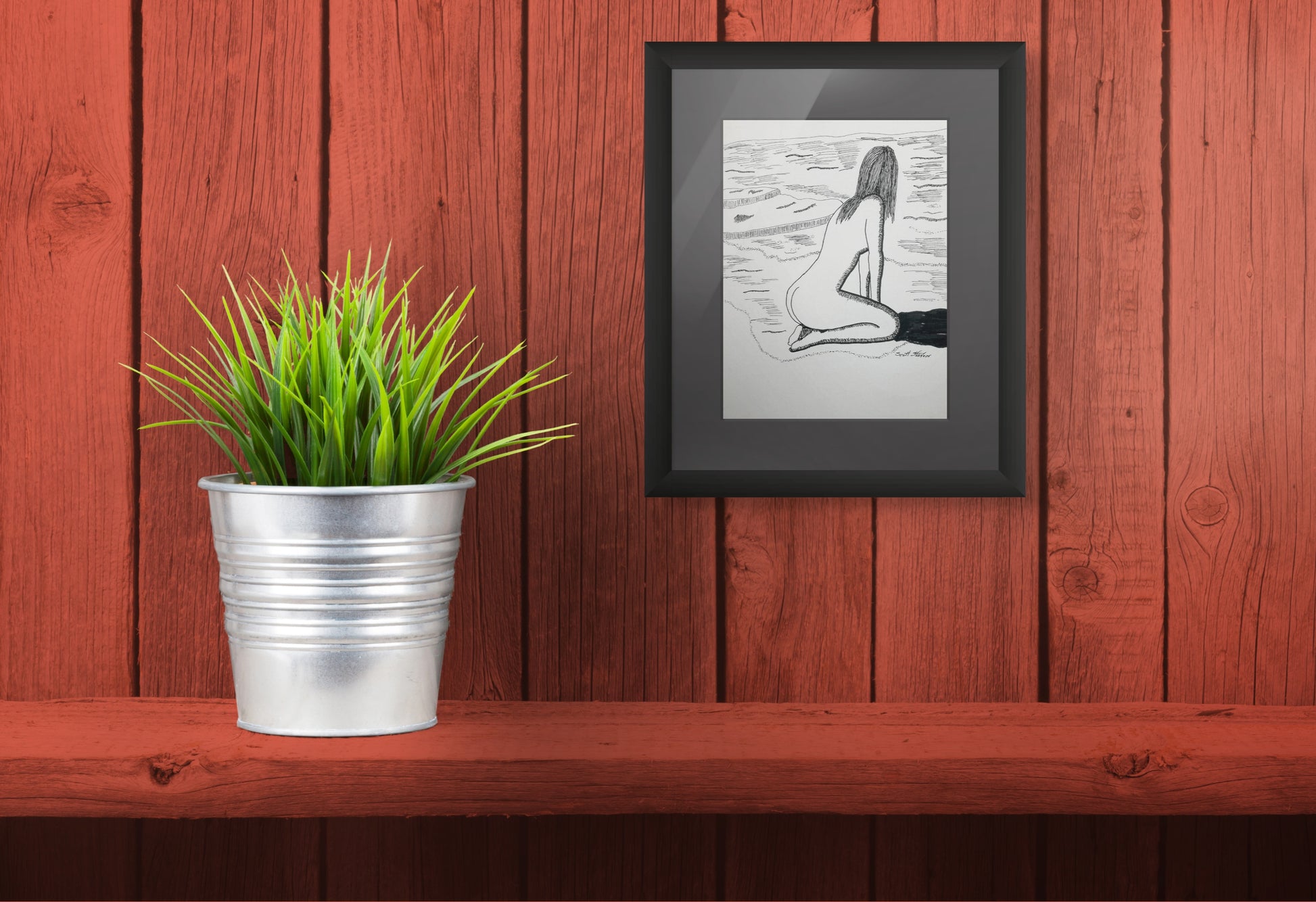 Framed black and white artwork of a nude figure on a wooden shelf with a potted plant.