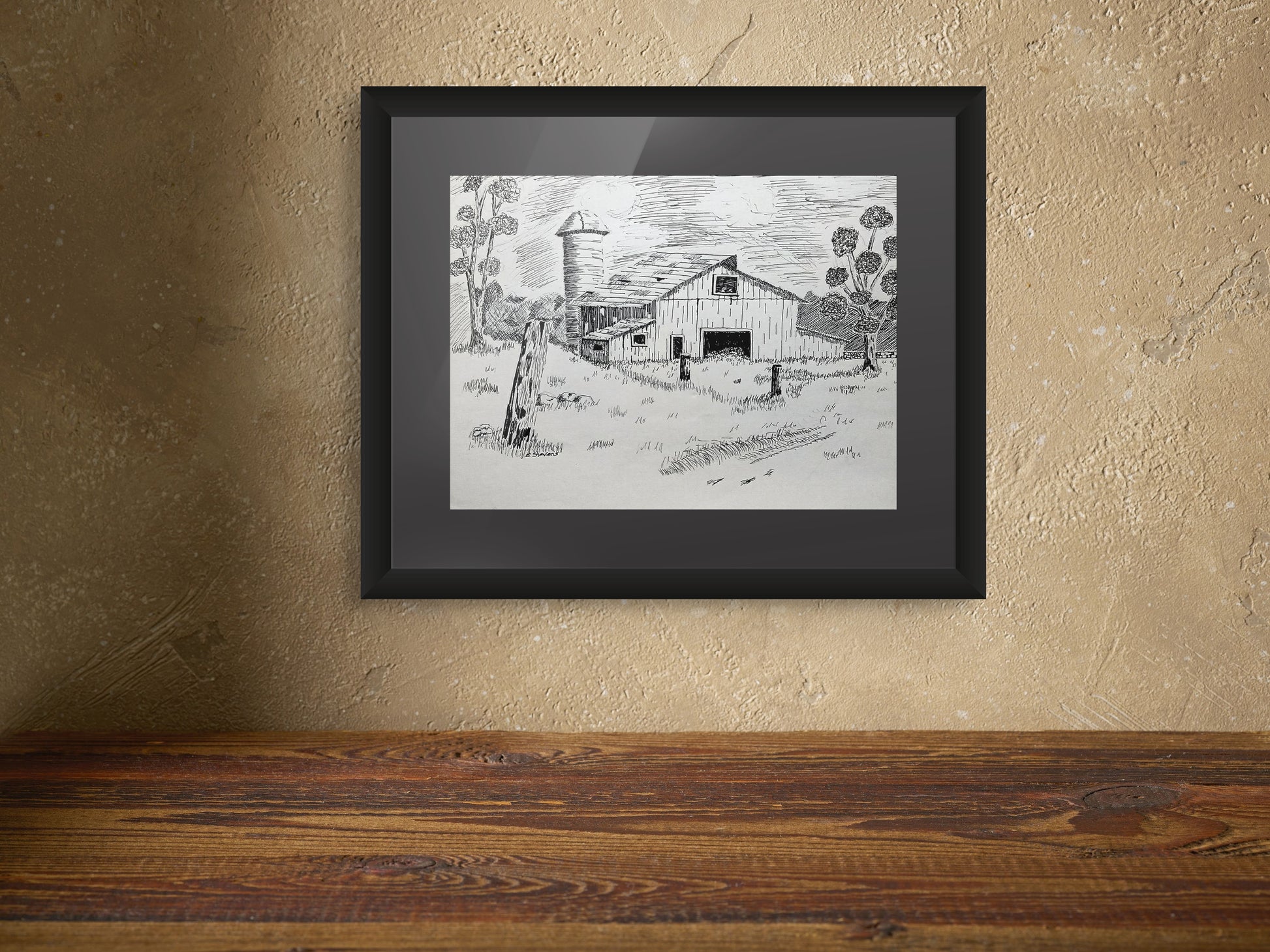 Framed black and white drawing of a farm scene on a textured wall.