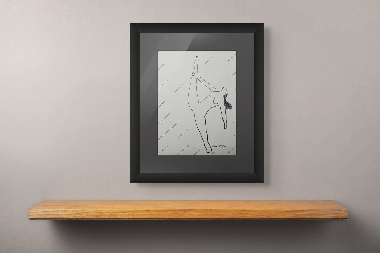 Framed black and white drawing of a dancer on a wooden shelf against a gray wall.