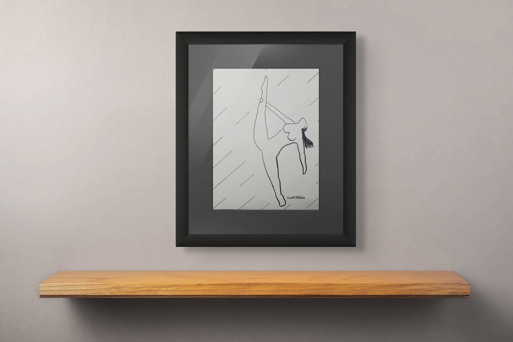Framed black and white drawing of a dancer on a wooden shelf against a gray wall.