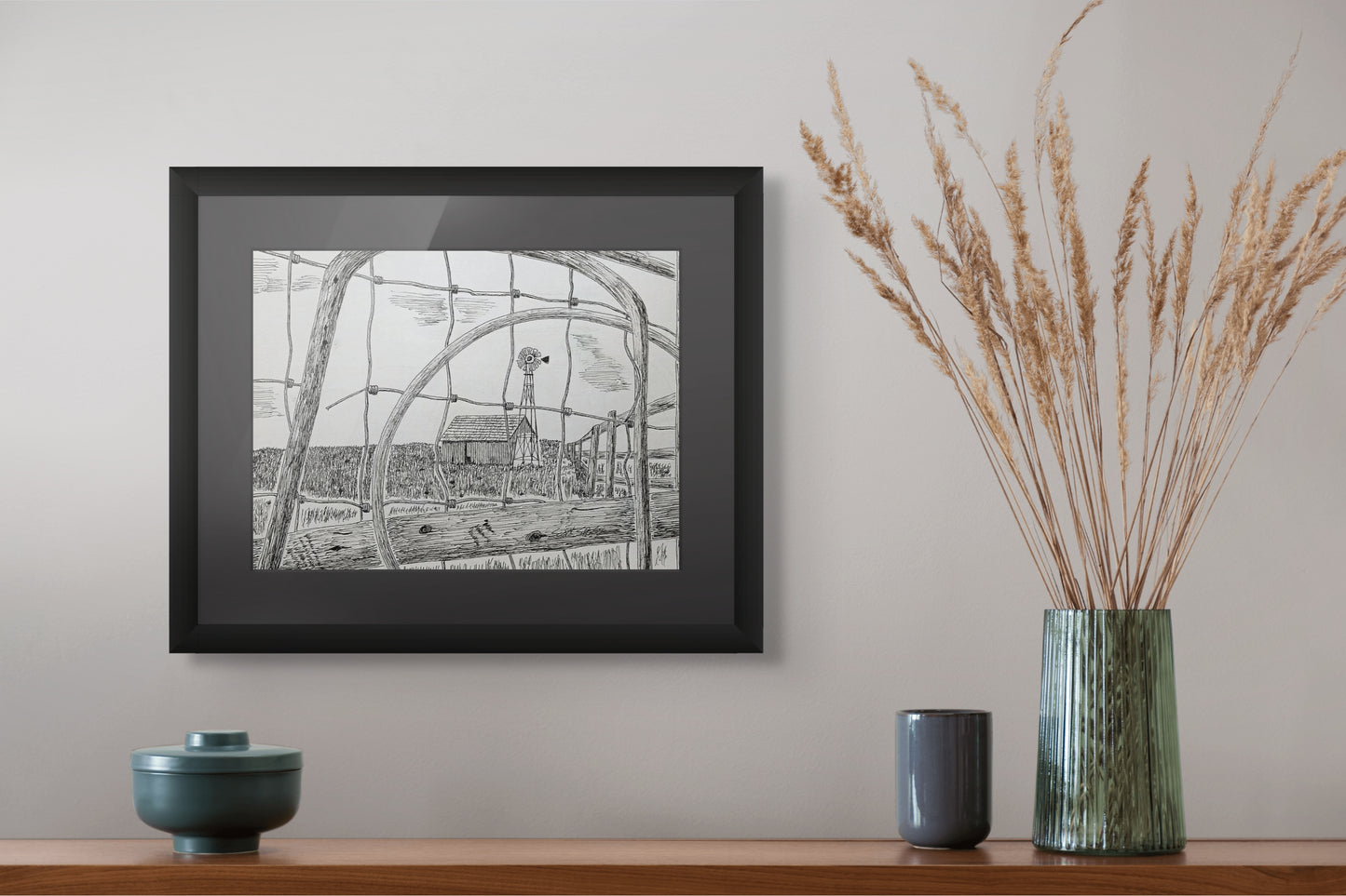 Framed black and white print on a wall above a wooden shelf with decorative items.