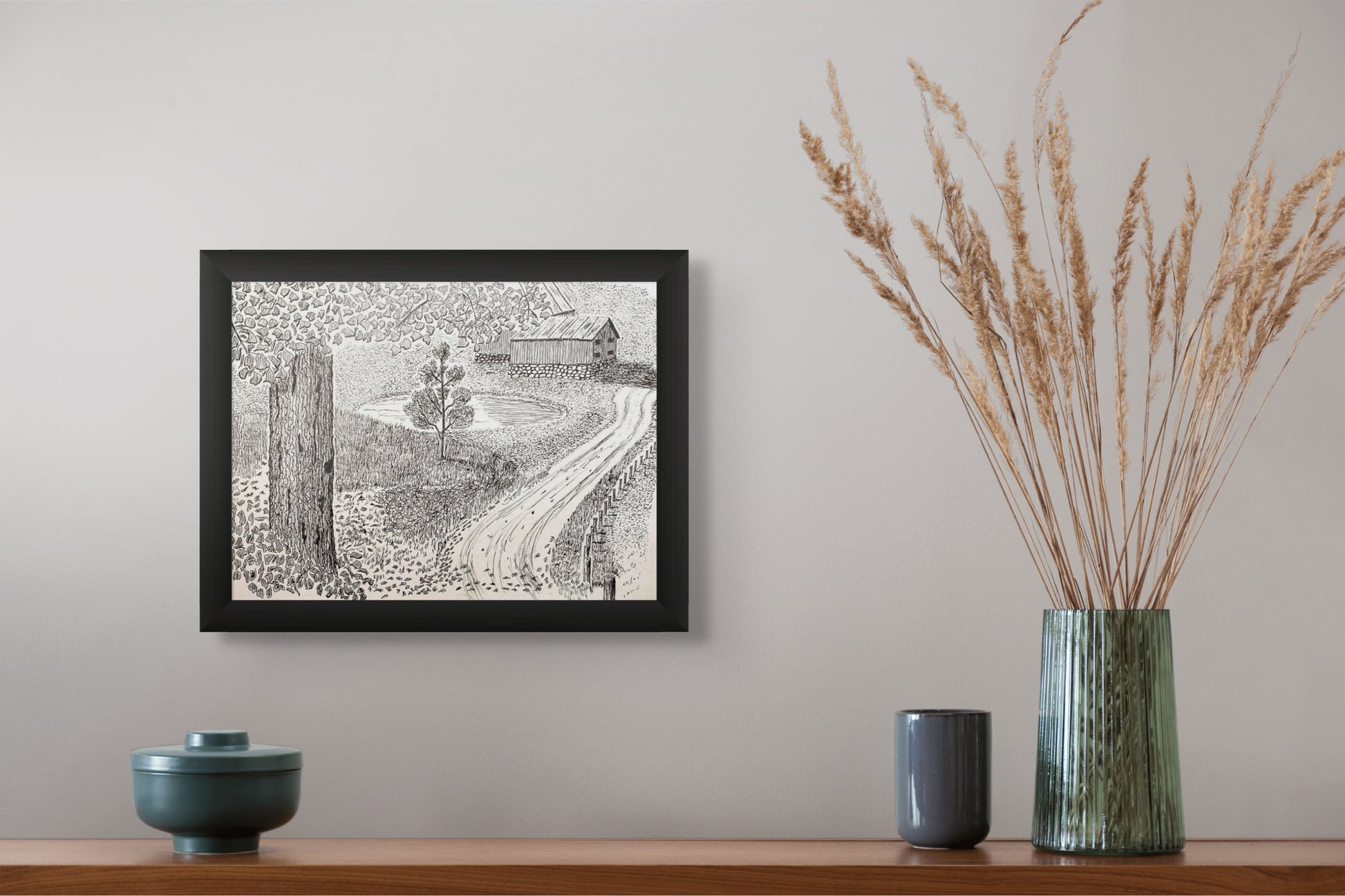 Framed black and white print on a wall above a wooden shelf with decorative items.